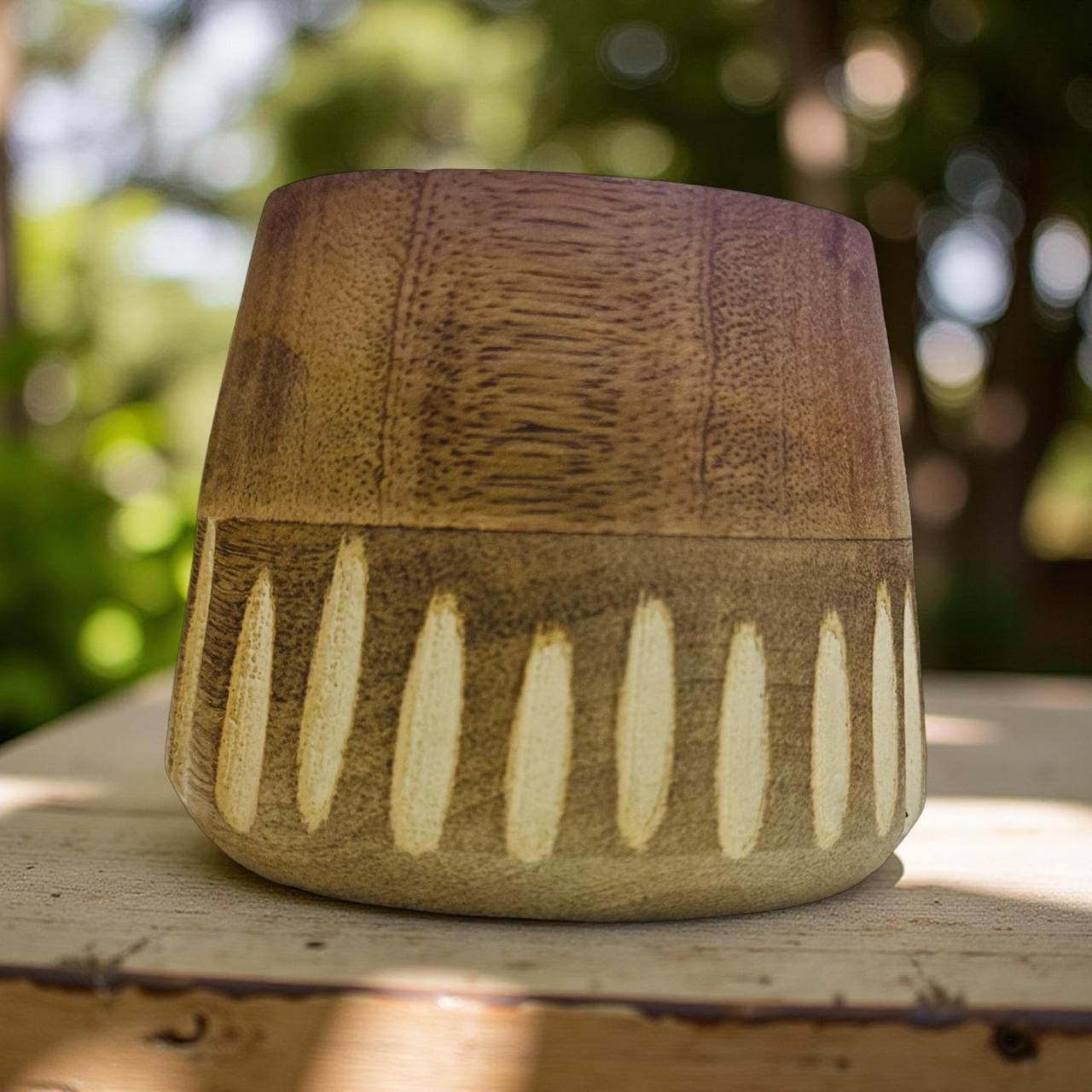 wooden pot with textured design on a wooden surface outdoors