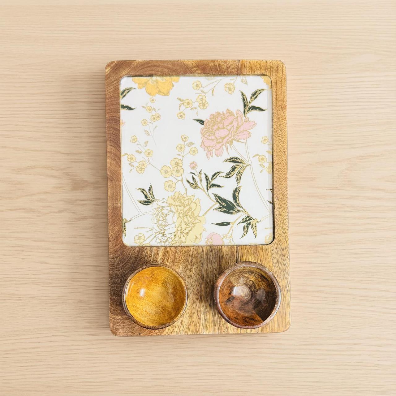Wooden tray with floral design and two small bowls on a wooden surface