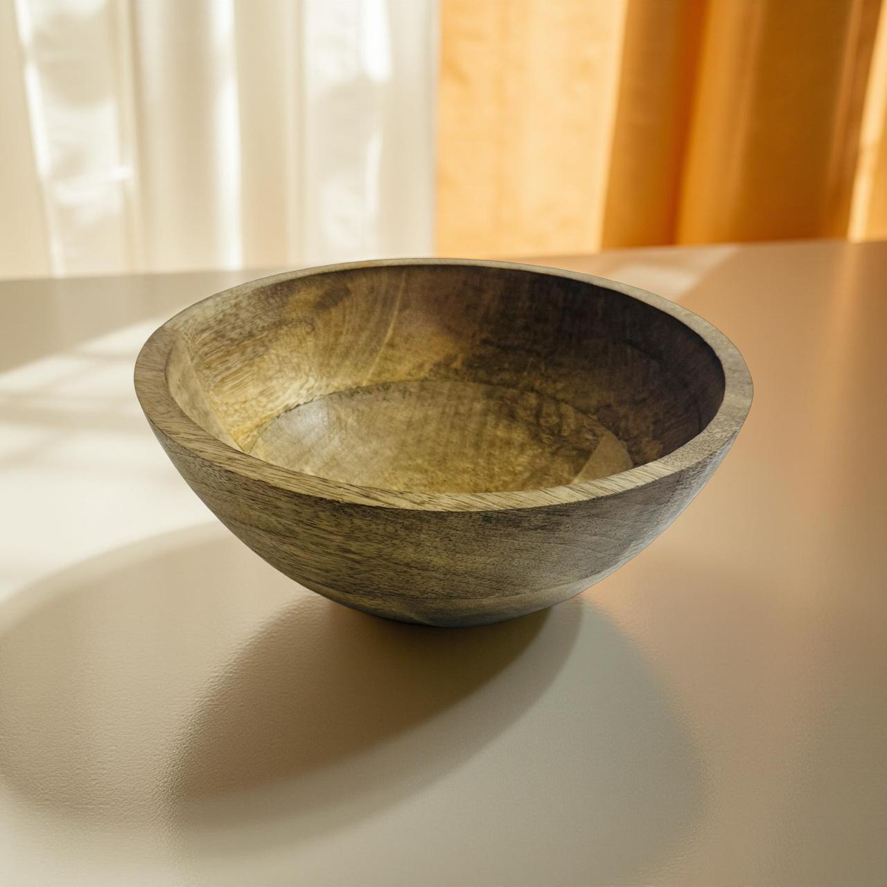 Wooden bowl on a light surface with curtains in the background