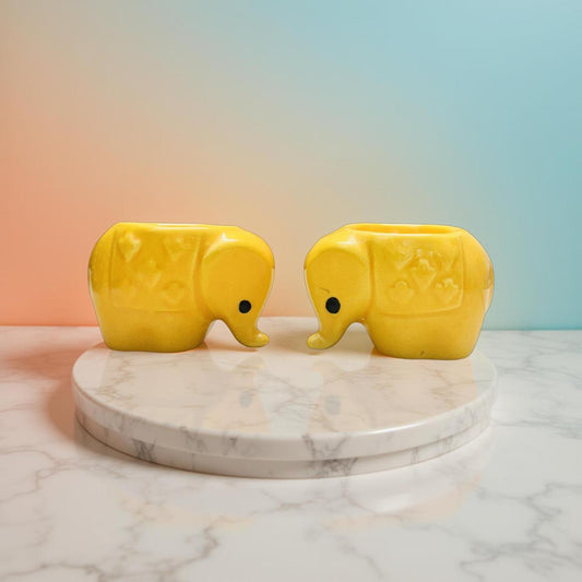 Two yellow elephant-shaped objects on a marble platform with a gradient background
