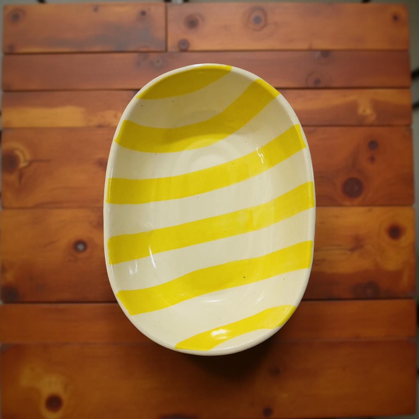 Yellow and white striped ceramic plate on a wooden surface