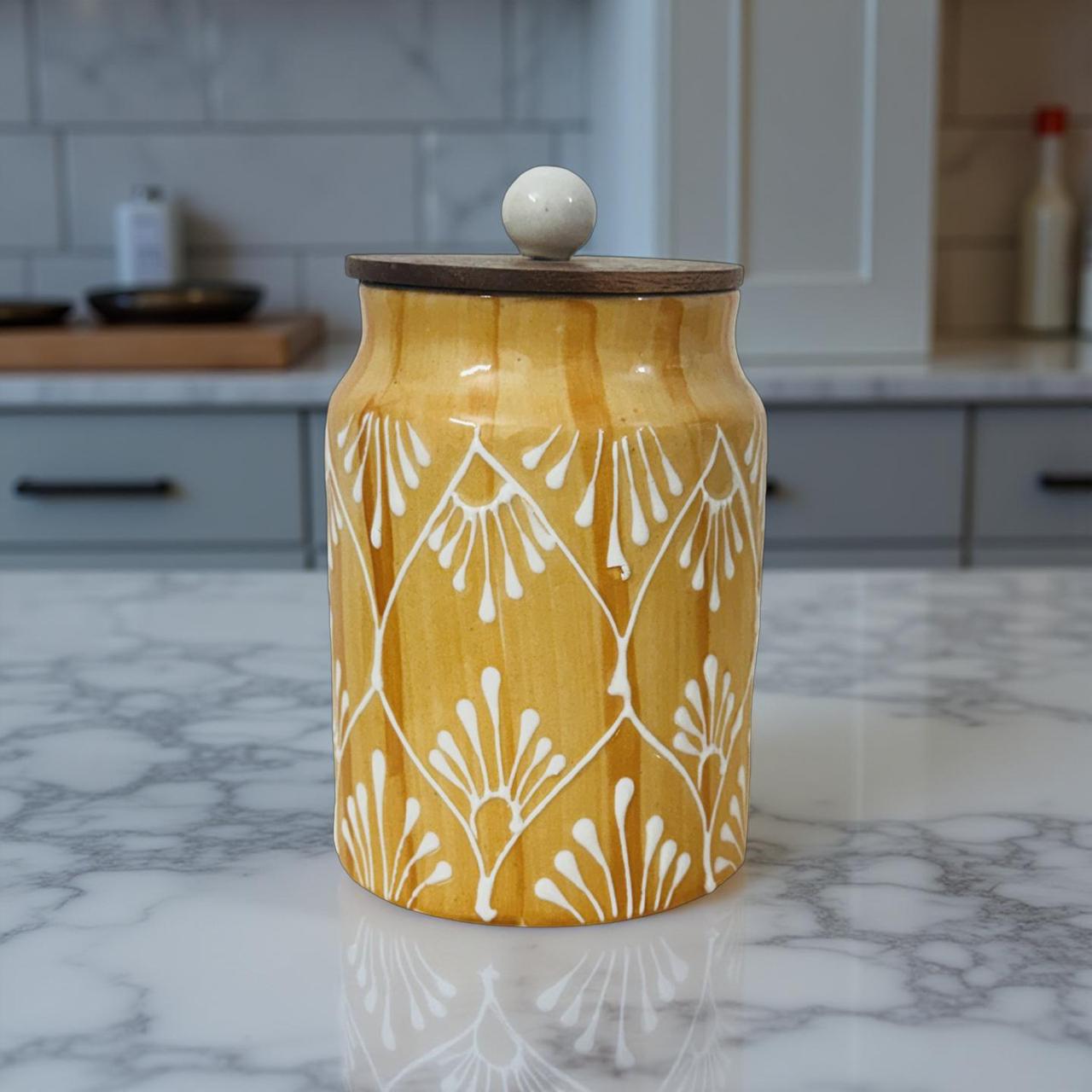 Yellow ceramic jar with white patterns on a marble countertop in a kitchen.