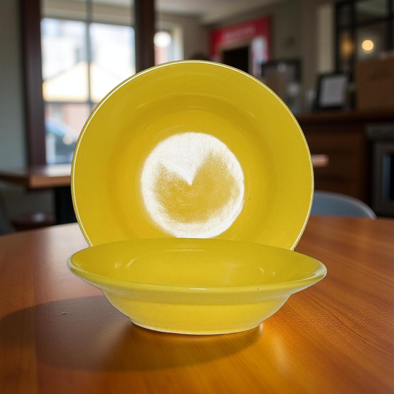 yellow ceramic soup and pasta bowl set on a wooden table with natural light.