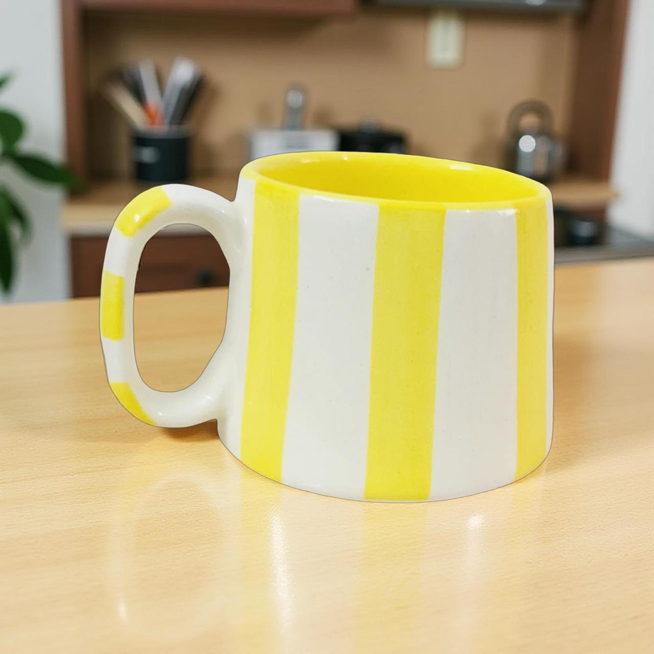 Yellow and white striped mug on a wooden table with a kitchen background
