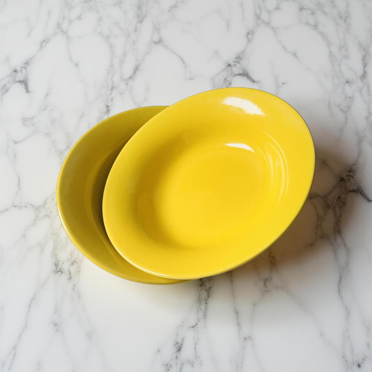 Two yellow plates stacked on a marble surface