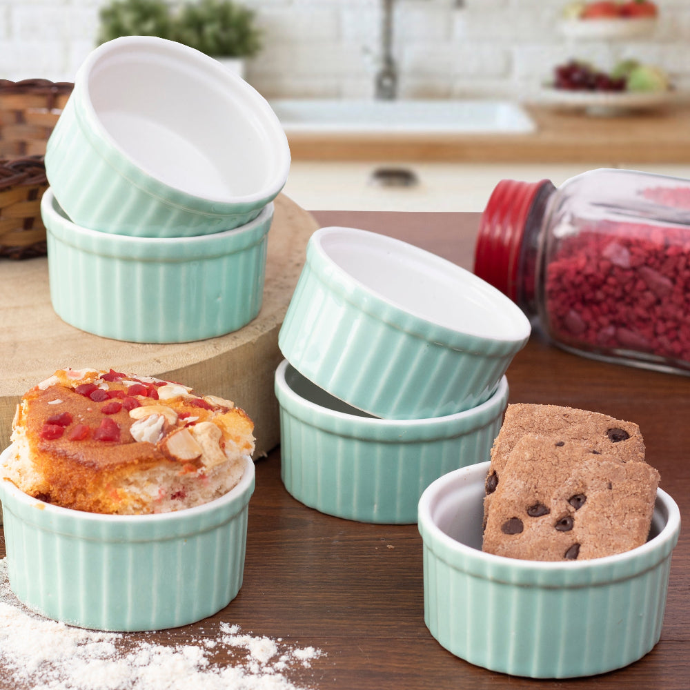 Hand holding a ceramic ramekin bowl next to baking tray