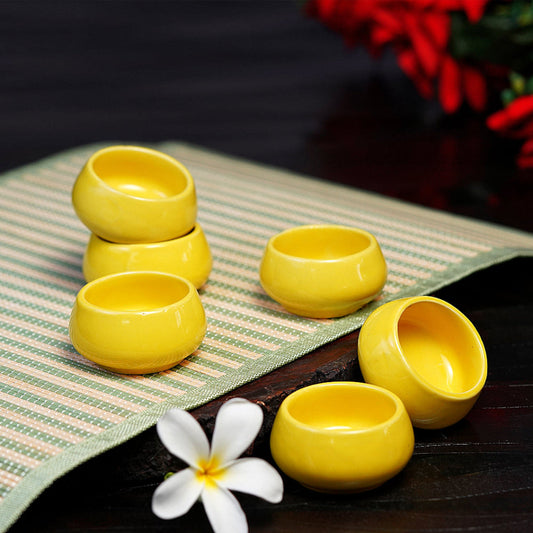 Soft-hued dip bowls beside a tea set on a wooden tray